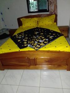 雅温得Pauline的一张带黄色棉被和黑白毯子的木床