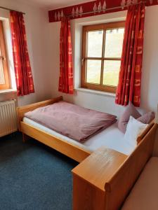 容霍尔茨缪勒农家乐的一间卧室配有床和红色窗帘的窗户