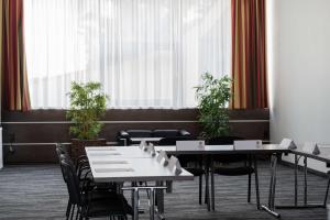 格拉茨Best Western Plus Plaza Hotel Graz的用餐室设有桌椅和窗户。