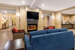 亨博尔东部IAH布什机场舒适套房酒店的客厅设有蓝色的沙发和壁炉