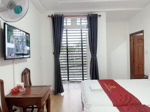 胡志明市Thiên Phát Hotel - SECC的一间卧室配有一张床、一张书桌和一台电视