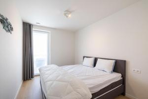尼乌波特VivaVela的一间卧室配有一张带白色床单的床和一扇窗户。