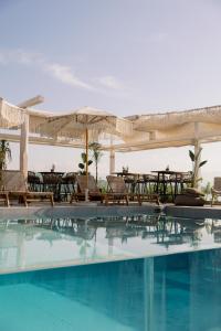 伊西翁LAS HOTEL & SPA的一个带桌椅的游泳池以及遮阳伞