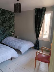 穆瓦萨克Auberge des chemins的一间卧室设有两张床、一把椅子和一个窗户。