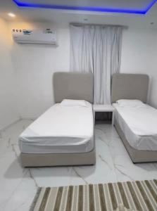 豪尔费坎Al Sharq Holiday Home的一间卧室设有两张床、一张桌子和一个窗口