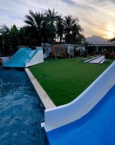 豪尔费坎Al Sharq Holiday Home的一个带滑梯和游乐场的大型游泳池