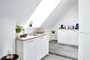 施韦青根Schlossberg Residences - XXL-Design-Apartment mit Schlossblick für bis zu 10 Personen的厨房配有白色橱柜和水槽