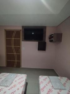 圣贝尔纳多-杜坎普Hotel Simba的小房间设有两张床和一台墙上的电视