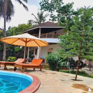 Galumanuastro Breeze Villa的房屋旁的游泳池配有遮阳伞和椅子