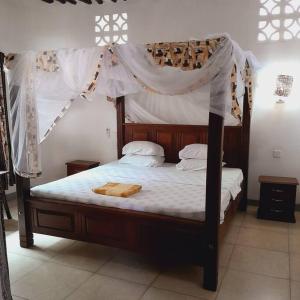 GaluManuastro Breeze Villa - Diani Beach的一间卧室配有一张木床和天篷