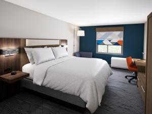 奥蒙德海滩Holiday Inn Express & Suites Ormond Beach - North Daytona, an IHG Hotel的卧室配有一张白色大床和一张书桌