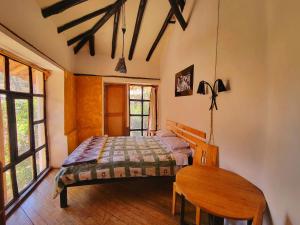 乌鲁班巴Logde Casa de campo & Retreat Center的一间卧室配有一张床和一张木桌