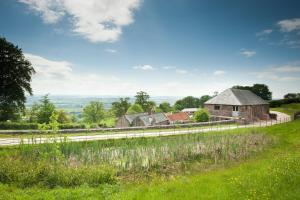 West BagboroughTilbury Shepherd Huts with Hot Tubs Plus Holiday Cottages的山坡上一座古老的房子,毗邻一条道路