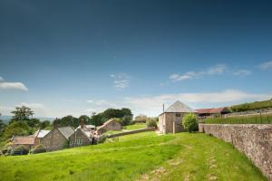 West BagboroughTilbury Shepherd Huts with Hot Tubs Plus Holiday Cottages的绿色的田野,有房子和石墙