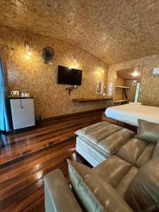 Tha Kradanธารามนตรา รีสอร์ท (Taramontra resort)的一间卧室配有一张床、一张沙发和一台电视。