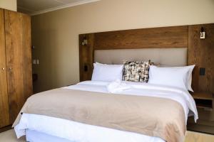 温特和克Windhoek Gardens Boutique Hotel的卧室配有一张白色大床和木制床头板
