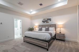 休斯顿New! Houston Luxury Haven near Dwtn, Med CTR的一间白色卧室,配有一张床和一个带两盏灯的床头柜