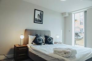伯明翰Stunning 2-Bed Apartment in Birmingham City Center的一间卧室配有一张带白色床单的床和一扇窗户。