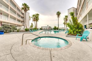 科珀斯克里斯蒂Beachfront Corpus Christi Condo with Pool Access!的庭院内的游泳池,配有椅子和棕榈树