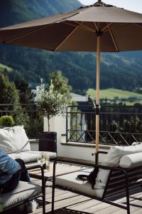 蓬高圣约翰Alpina Alpendorf的天井配有遮阳伞、2把椅子和1张桌子