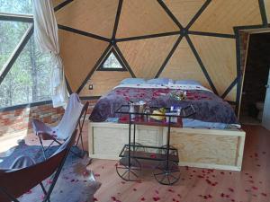 OtinapaGlamping Town的帐篷内的卧室,配有一张床和椅子