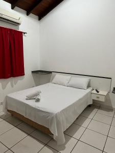 蓬塔波朗HOTEL MARAMBAIA的卧室配有白色的床和红色窗帘