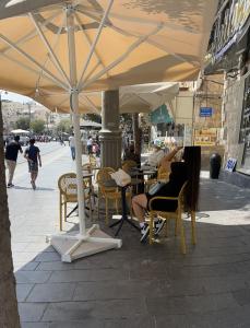 耶路撒冷La Provençale的坐在椅子上,在街上的伞下坐着的女人