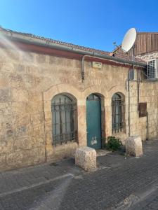 耶路撒冷La Provençale的一座石头建筑,设有绿门和两个石凳