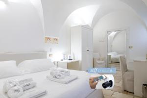 卡洛维诺Dimora Dell'Osanna Raro Villas Smart Rooms Collection的白色客房,配有带毛巾和镜子的床