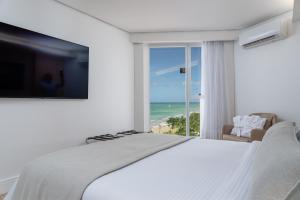 马塞约Hotel Brisa Suítes Pajuçara的一间卧室配有一张床,享有海景