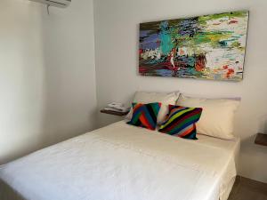 阿帕尔塔多Casa hotel Mateguadua的一张带两个枕头的白色床和墙上的绘画
