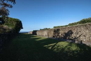 大里贝拉ENTRE MUROS - Turismo Rural - Casa com jardim e acesso direto ao mar的草地上带阴影的古老石墙