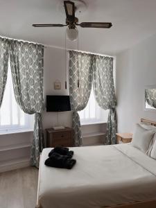 直布罗陀Engineer Lane House的卧室配有白色的床、窗帘和风扇