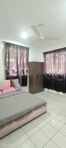 TuaranSantai Homestay的一间卧室配有一张带粉红色窗帘的大床