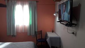 El CarmenLa Nona的卧室配有一张桌子和一张床,墙上配有电视