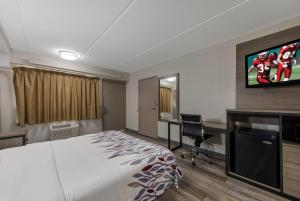 希科里锡克里红屋顶客栈的配有一张床和一台平面电视的酒店客房