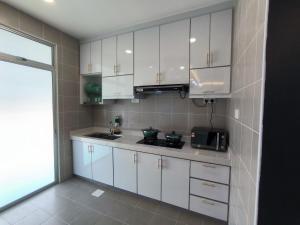 芙蓉Homestay Naufal Bandar Sri Sendayan Ground Floor的厨房配有白色橱柜、水槽和微波炉