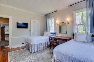 奥古斯塔Noble Cottage 3 Bed 1 Bath的一间卧室设有两张床、一张桌子和一个窗口。
