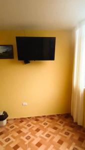 利马Pretty room in front of the Lima Airport的客房在黄色墙壁上配有平面电视。