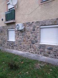 KomlóJószerencsét apartman的建筑中带两扇窗户和扬声器的石墙