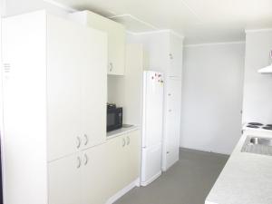 WairoaThe Mitch的厨房配有白色橱柜和冰箱。