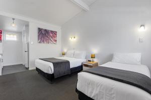 阿德莱德Econo Lodge East Adelaide的一间酒店客房,设有两张床和走廊