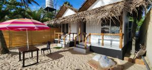阿勒皮Bliss Beach Villa的一个带雨伞、椅子和桌子的房子