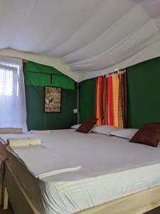 维勒珀图Nirvaan Safari Lodge的一张白色大床,位于带绿色墙壁的房间
