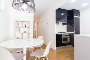 巴塞罗那L'alzina Apartment的厨房以及带白色桌椅的用餐室。