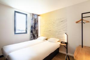 贝桑松B&B HOTEL Besançon Valentin的酒店客房设有两张床和窗户。