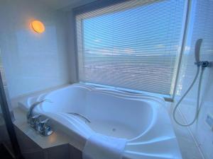 札幌札幌王子酒店的带浴缸、水槽和窗户的浴室
