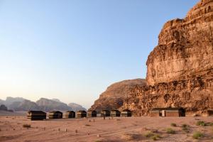 瓦迪拉姆Wadi rum galaxy camp的悬崖边沙漠中的一群住所