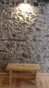 弗雷舒德埃什帕达阿辛塔Casinhas de S. Francisco T2 Azeitona by LovelyStay的石墙前的木凳