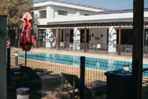 约翰内斯堡Sizakele Stays的一个带红色遮阳伞和椅子的游泳池以及一座建筑